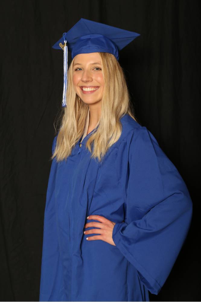 woman wears her cap and gown for a picture at GradFest